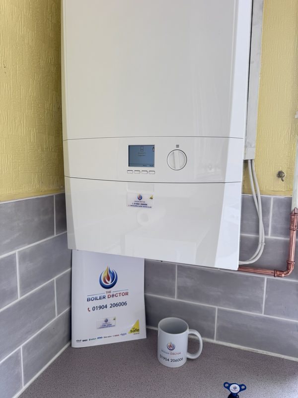 Finished boiler installation with a Boiler Doctor branded folder and mug